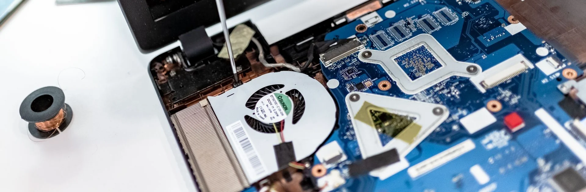 Detalhe de uma bancada durante a manutenção de componentes internos de um laptop