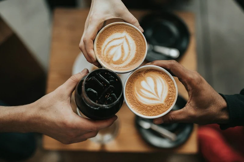 Xícaras de cappuccino com arte latte erguidas em brinde